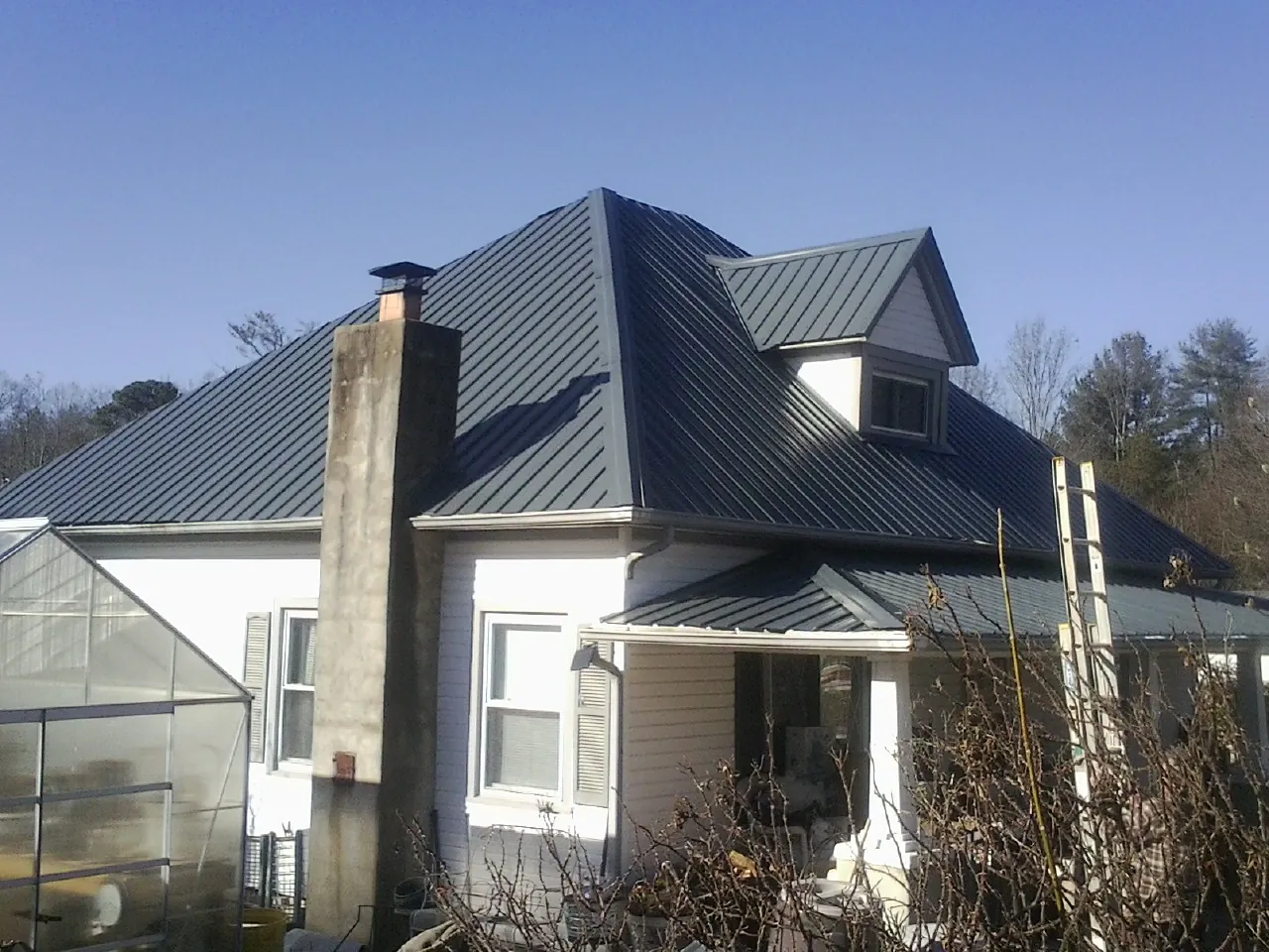 Dark blue standing seam metal roof on a white farmhouse with dormer — Slate & Tile Roof Repair by Roofing Brothers in Rixeyville