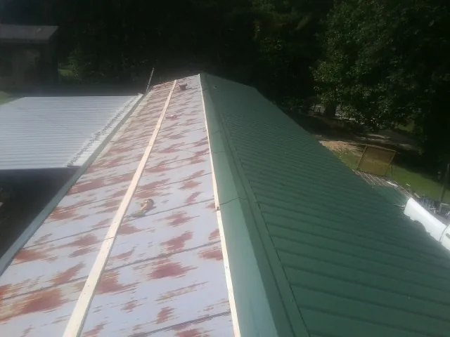 Old rusted panels beside newly installed green metal roofing — Wind Damage Roof Repair by Roofing Brothers in Rixeyville
