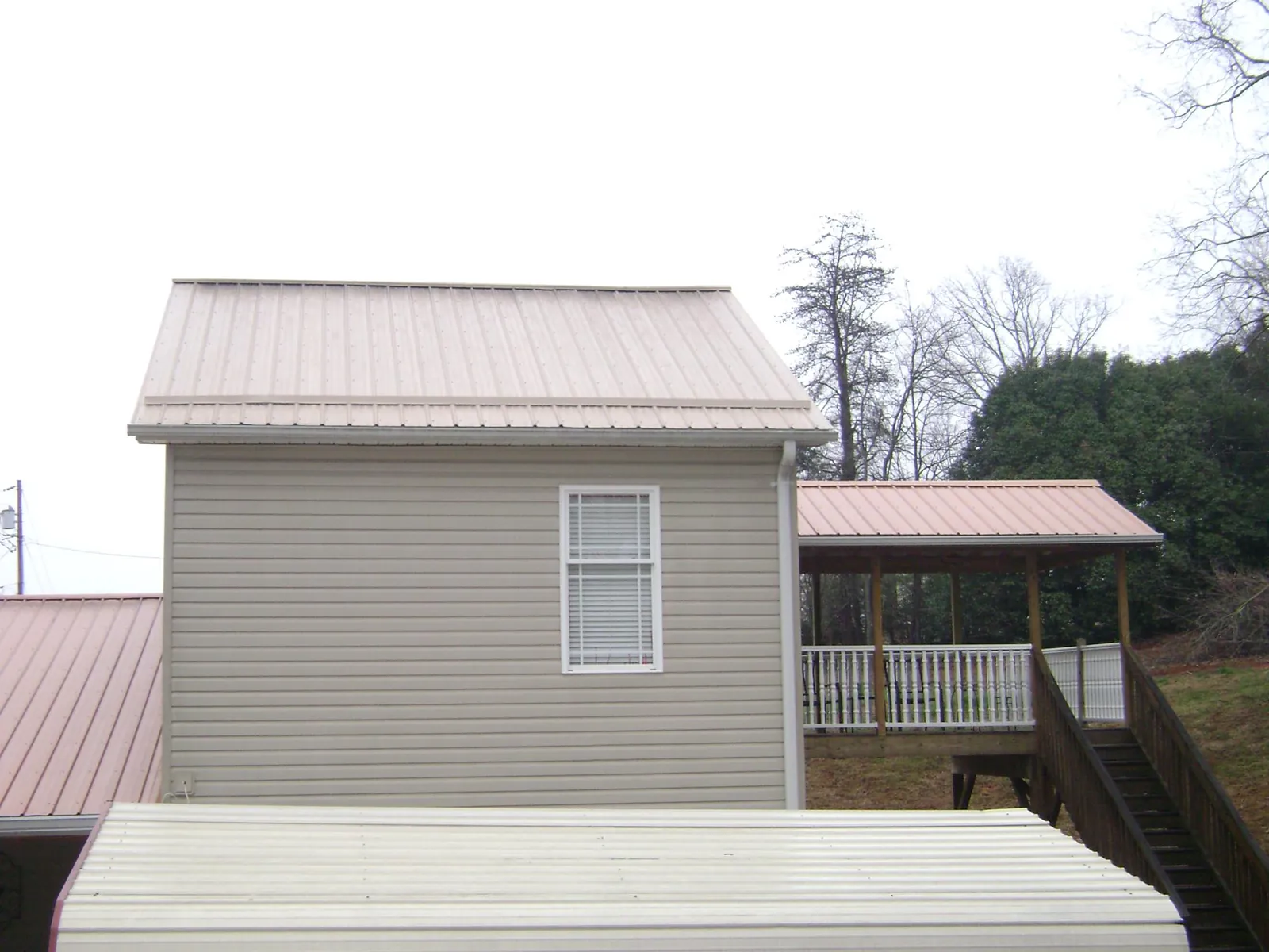 Tan metal roofs on a two story addition and attached porch, from a Roof Replacement job in Rixeyville